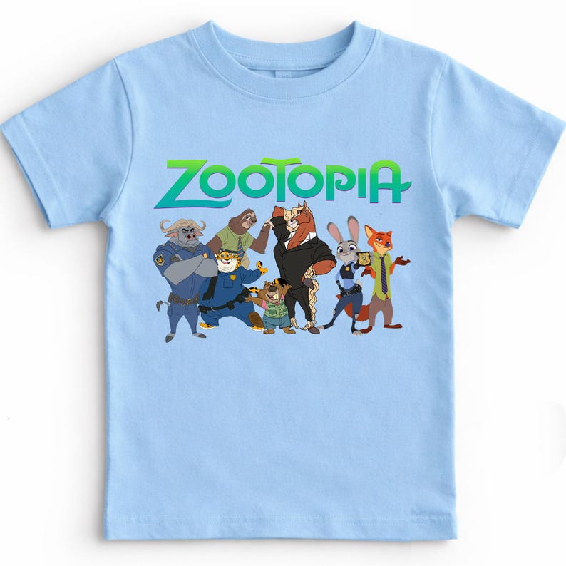 K&ouml;nnte beinhalten: Ein hellblaues T-Shirt mit dem Wort "ZOOTOPIA" in Gr&uuml;n und einer Gruppe von Zeichentrickfiguren. Die Figuren umfassen einen Polizisten, ein Faultier, einen Tiger, ein Pferd, ein Kaninchen und einen Fuchs.