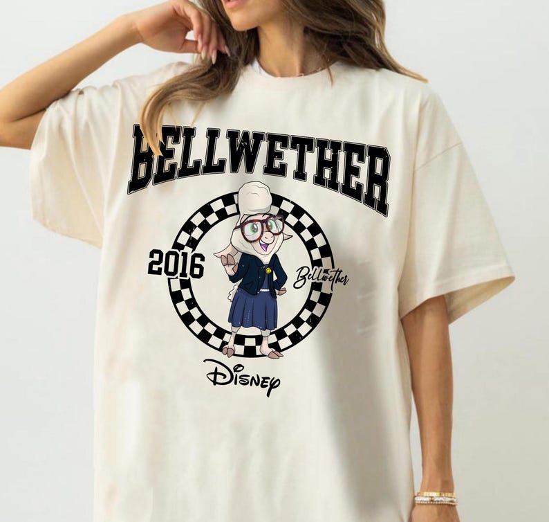 May include: An off-white t-shirt featuring a graphic of the character Bellwether from Disney. The design includes the text BELLWETHER, 2016, and Disney, centred within a black and white checkered circle. The character wears glasses and a blue outfit.
