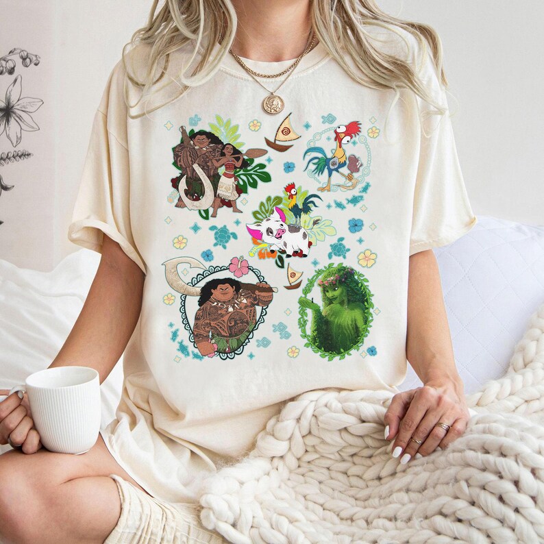 May include: Cream-colored t-shirt featuring colorful cartoon illustrations of characters from a popular animated movie. The design includes images of a man, woman, rooster, pig, and other elements, surrounded by floral and nautical motifs.