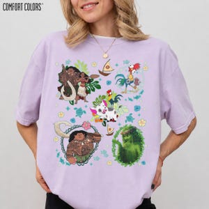 May include: A light purple Comfort Colors t-shirt featuring colorful cartoon graphics of characters from a popular animated movie. The graphics include characters, boats, and floral elements. The shirt is a relaxed fit.
