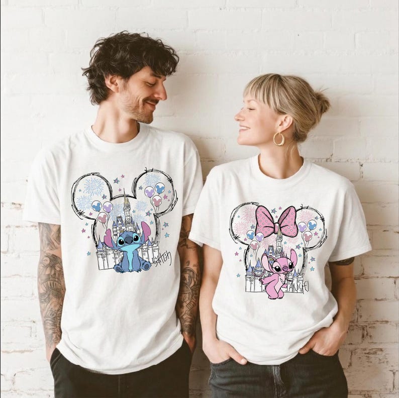 Puede incluir: Dos camisetas blancas de manga corta con estampados gr&aacute;ficos de personajes de Disney. La camiseta de la izquierda muestra al personaje Stitch azul con un castillo y fuegos artificiales dentro de una silueta de Mickey Mouse. La derecha muestra a Angel.