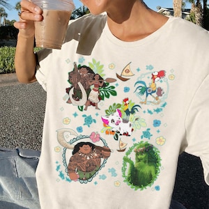 May include: Cream-colored t-shirt featuring colorful cartoon illustrations of characters from a popular animated movie. The design includes images of a rooster, pig, and other characters, surrounded by floral and nautical elements.