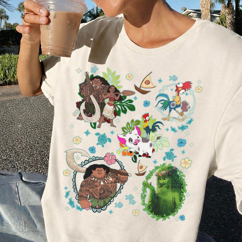 May include: Cream-colored t-shirt featuring colorful cartoon illustrations of characters from a popular animated movie. The design includes images of a rooster, pig, and other characters, surrounded by floral and nautical elements.