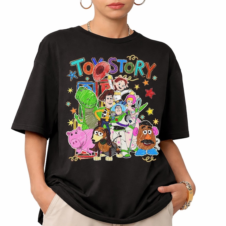 Może przedstawiać: Czarny t-shirt z kolorową grafiką postaci z filmu animowanego "Toy Story". Projekt zawiera Chudego, Buzz'a Astrala, Rexa i inne postacie, ze słowami "Toy Story" w zabawnej czcionce. Koszulka ma kr&oacute;tkie rękawy.