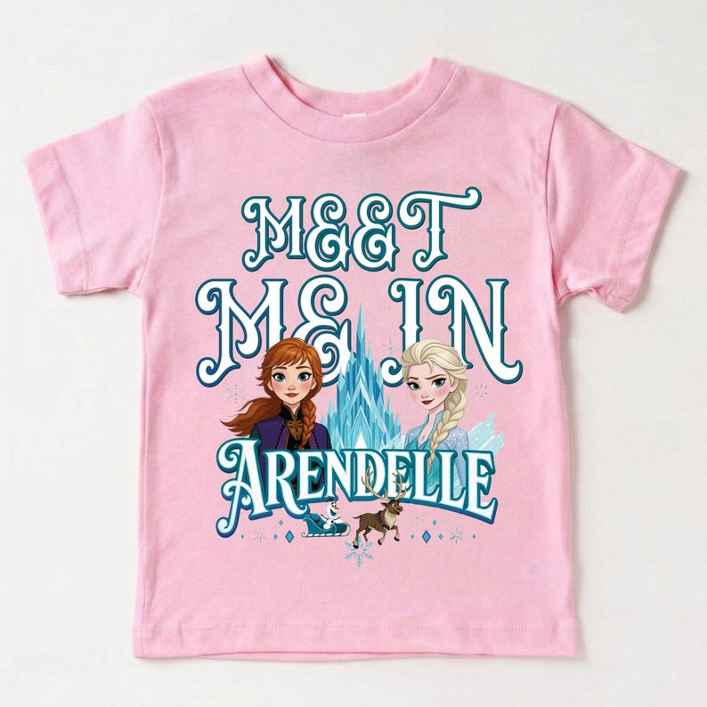 May include: Pink short-sleeved t-shirt featuring the text "MEET ME IN ARENDELLE" in teal script. The design includes illustrations of two animated characters, a castle, and a reindeer.