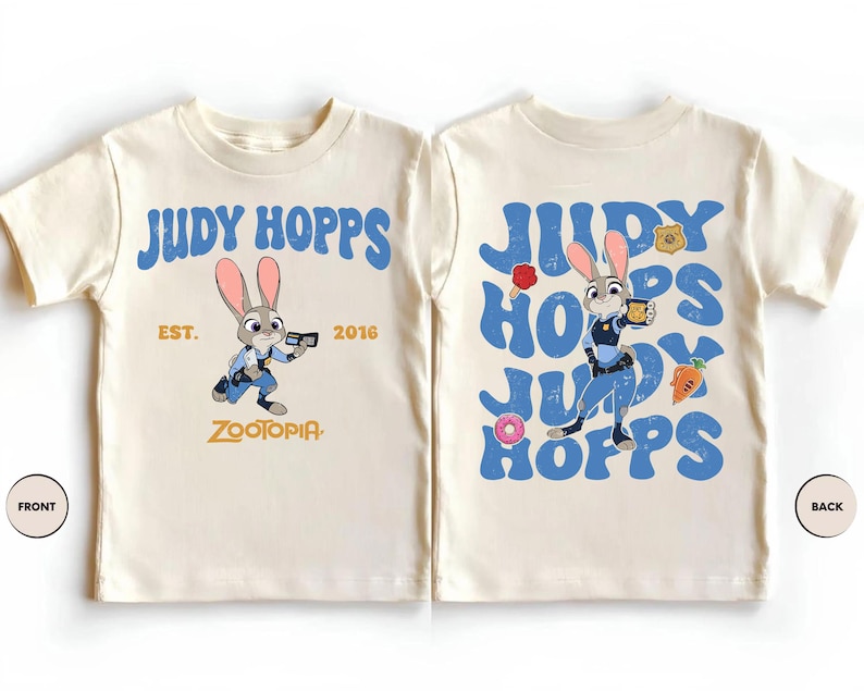May include: A cream-colored t-shirt featuring Judy Hopps from Zootopia. The front displays the character with the text Judy Hopps, Est. 2016, and Zootopia. The back shows the character surrounded by repeating blue text and small icons.