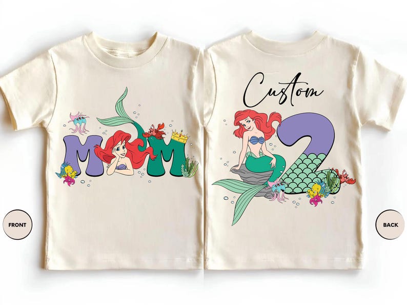 May include: Cream-colored toddler t-shirts with a mermaid theme. The front features the word "MOM" with a mermaid illustration. The back has a mermaid illustration with the number "2" and the word "Custom".