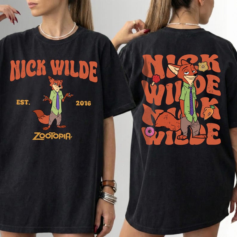 Pode incluir: Uma t-shirt preta com um gr&aacute;fico da personagem Nick Wilde de Zootopia. A frente apresenta o texto NICK WILDE EST. 2016 ZOOTOPIA. As costas mostram uma ilustra&ccedil;&atilde;o maior da personagem com o texto repetido NICK WILDE.