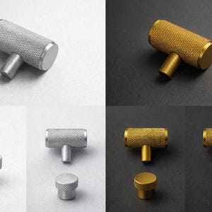 May include: A selection of cabinet knobs in silver and gold. The knobs feature a textured, cylindrical body with a T-shaped stem. The silver knobs are displayed against a white backdrop, and the gold knobs are on a black background.