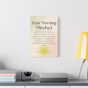 May include: A motivational canvas print with the text "Your Morning Mindset". The print features a soft, neutral color palette with a sunrise graphic at the bottom. The text includes positive affirmations for the day.