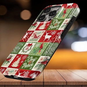 Könnte beinhalten: Eine Smartphone-Hülle mit festlichem Patchwork-Design in Rot, Grün und Weiß. Das Muster zeigt Illustrationen von Kardinälen, Rentieren, Weihnachtsbäumen, Kränzen und Schneeflocken sowie den Text Joy, Peace und Sleigh Rides.
