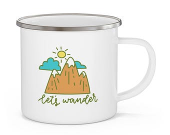 May include: White enamel camping mug with a silver rim and handle. The mug features a cartoon illustration of mountains, clouds, and a sun, with the text "let's wander" in green cursive. A perfect gift for outdoor enthusiasts.