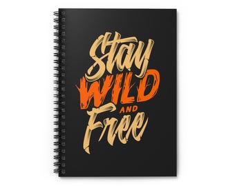 May include: Black spiral-bound notebook with the words "Stay Wild and Free" in orange and tan lettering. The notebook has a black cover and a silver spiral binding. The text is stylized with a bold, handwritten font.