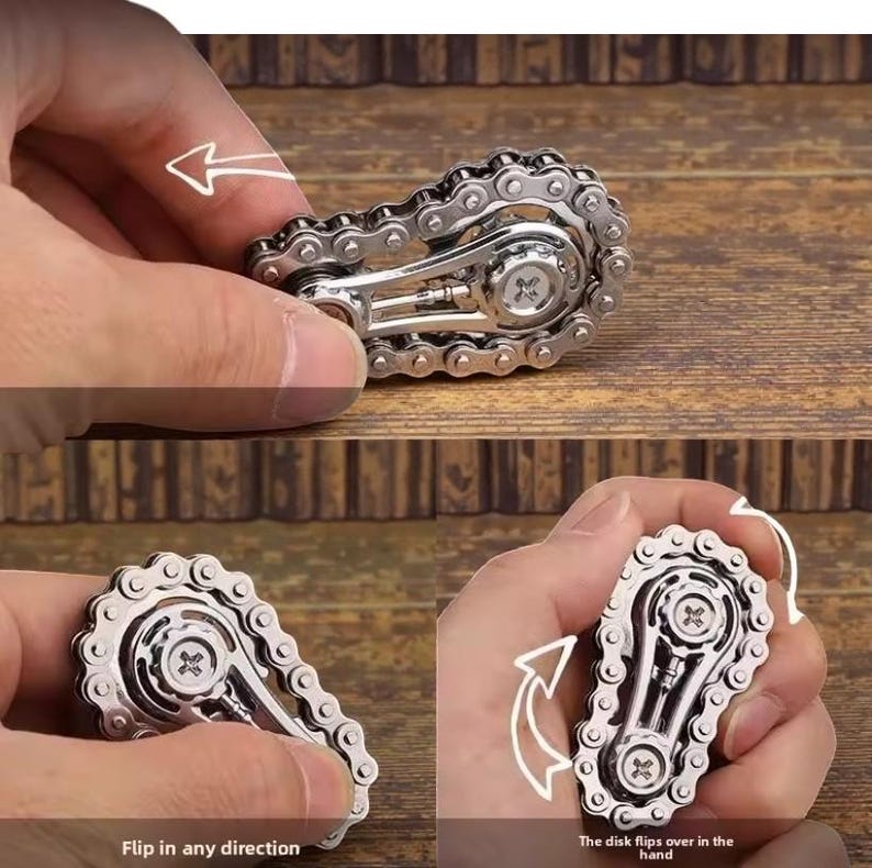 May include: A silver-colored fidget toy resembling a bicycle chain. The toy has a central disk with a cross-shaped design and is held in a person's hand. The text "Flip in any direction" and "The disk flips over in the hand" are visible.
