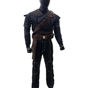 May include: Black costume with white stitching details, displayed on a mannequin. The outfit includes a long-sleeved top, pants, and a brown leather belt with a holster. The mannequin has a black head and gloves.