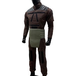 May include: A brown and black costume on a mannequin. The outfit includes a high collar, shoulder padding, and a green waist protector. The trousers have black knee patches. The mannequin has a black head and hands.