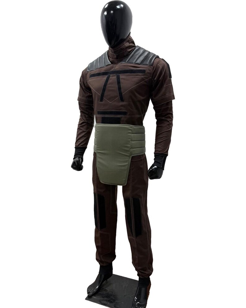 May include: A brown and black costume on a mannequin. The outfit includes a high collar, shoulder padding, and a green waist protector. The trousers have black knee patches. The mannequin has a black head and hands.