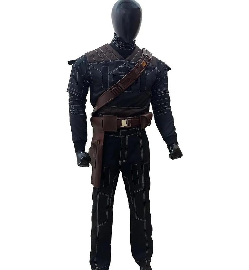 May include: Black costume with white stitching details, displayed on a mannequin. The outfit includes a long-sleeved top, pants, and a brown leather belt with a holster. The mannequin has a black head and gloves.