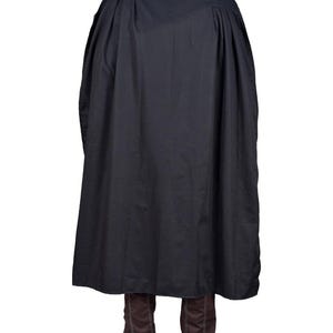 May include: A black cloak with a high collar and a flowing design. The cloak is made of a dark fabric and falls to the ankles. Brown boots are visible beneath the cloak. The garment appears to be a costume or theatrical wear.