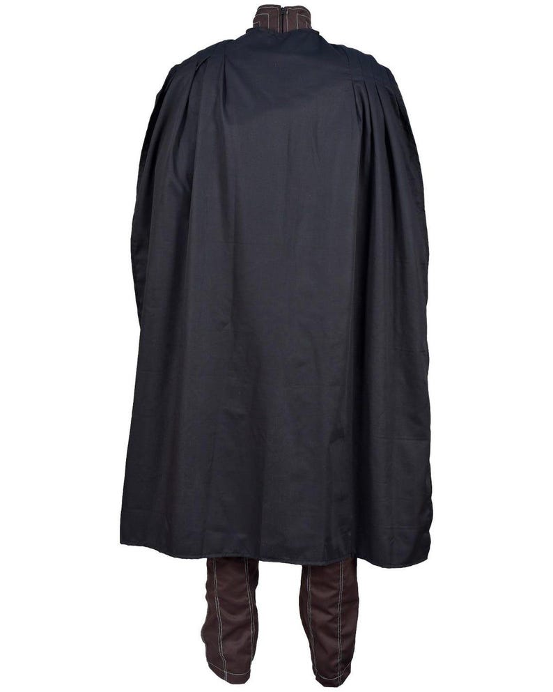 May include: A black cloak with a high collar and a flowing design. The cloak is made of a dark fabric and falls to the ankles. Brown boots are visible beneath the cloak. The garment appears to be a costume or theatrical wear.