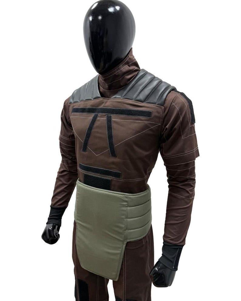 May include: Brown and black costume with a black helmet. The costume features a padded shoulder design, black accents, and a light green waist protector. The costume is displayed on a mannequin.