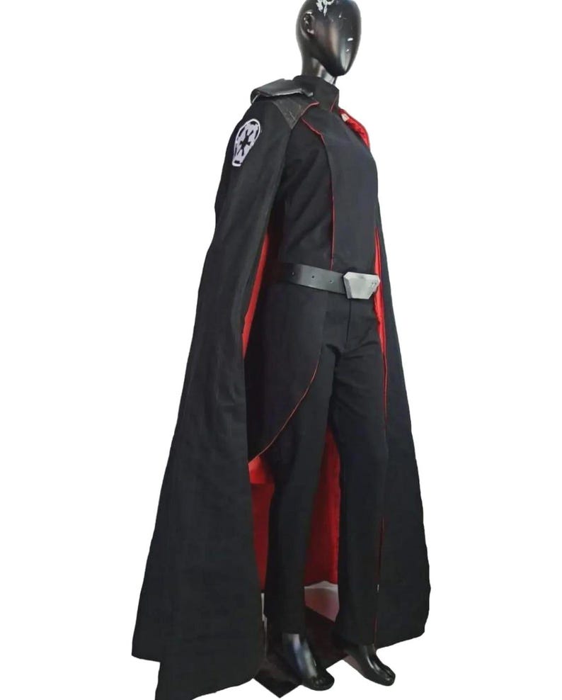 May include: A black costume with a long cape lined in red. The costume includes a black jacket, pants, and belt with a silver buckle. A white emblem is on the left shoulder. The costume is displayed on a mannequin.