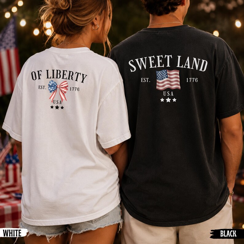 K&ouml;nnte beinhalten: Ein wei&szlig;es T-Shirt mit dem Text OF LIBERTY EST. 1776 USA und einer patriotischen Schleifengrafik sowie ein schwarzes T-Shirt mit dem Text SWEET LAND EST. 1776 USA und einer US-Flaggen-Grafik, beide mit drei kleinen Sternen unter den Motiven.
