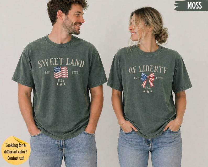 K&ouml;nnte beinhalten: Zwei kurz&auml;rmelige T-Shirts in Moosgr&uuml;n. Das linke T-Shirt zeigt den Text SWEET LAND, EST. 1776, USA und eine Grafik einer amerikanischen Flagge. Das rechte T-Shirt zeigt den Text OF LIBERTY, EST. 1776, USA und eine Grafik einer patriotischen Schleife.