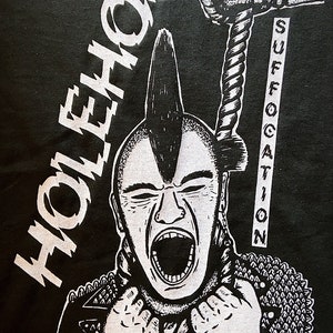 May include: Black and white graphic t-shirt featuring a punk rock character with a mohawk, wearing a leather jacket with spikes and holding a rope with a noose. The text "HOLEHOG" is printed on the left side of the shirt and "SUFFOCATION" is printed on the right side.