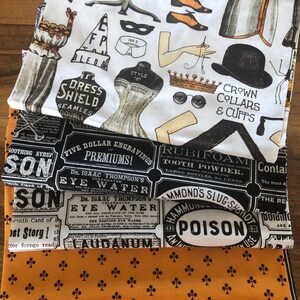 May include: A stack of fabric with various patterns. One fabric features vintage fashion illustrations, including a corset and shoes. Other fabrics display apothecary labels and a pattern of black clubs on an orange background. The bottom fabric has brown and white stripes.