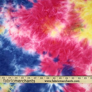 May include: A tie-dye fabric with a blue, pink, and yellow swirl pattern. The fabric is shown with a ruler for scale.