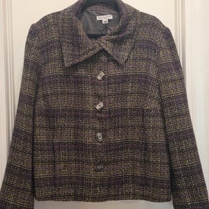 May include: A tweed jacket in shades of purple, gold, and brown, with a classic collar and three button closure. The jacket is hanging on a black hanger. The brand name "Pendleton" is visible on the label.