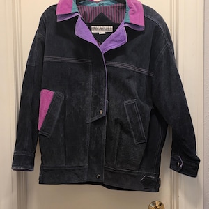 May include: Black suede jacket with purple and teal accents. The jacket features a purple collar and pocket detail, with the brand name "AVANTI" visible on the label. The jacket has a button closure and a belt detail at the waist.