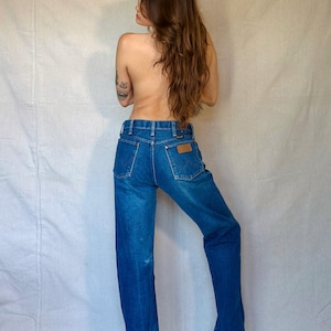 Person wearing blue jeans standing against a plain white background
