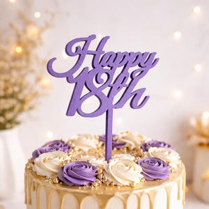 Könnte beinhalten: Eine Geburtstagstorte mit einem lila „Happy 18th“-Topper. Die Torte hat eine weiße Glasur mit einem lila Ombre-Effekt am Boden, goldenen Tropfen und ist mit lila und weißen Buttercremerosen und goldenen Streuseln verziert. Sie steht auf einem weißen Teller.