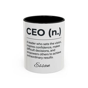 May include: A white ceramic mug with a black interior and rim. The exterior features the black text CEO (n.) followed by the definition: A leader who sets the vision, inspires confidence, makes difficult decisions, and empowers others to achieve extraordinary results. The name Essan is printed in a black script font at the bottom.