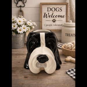 May include: A ceramic dog-shaped planter with a black and white color scheme. The planter has a white snout and a black nose. A wooden sign that says "DOGS Welcome (people tolerated)" is in the background.