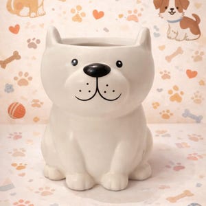 May include: A white ceramic dog-shaped planter with a black nose and smiling face. The planter has a round opening for plants and is decorated with paw prints, hearts, and dog illustrations.