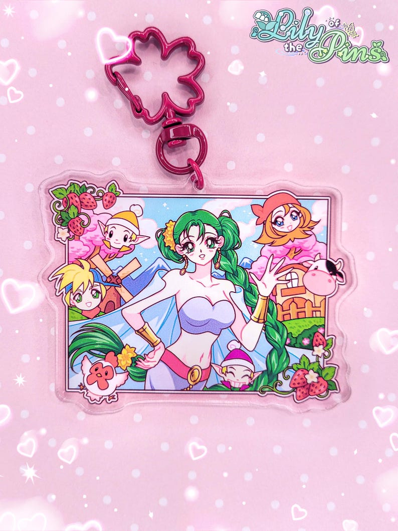 May include: A rectangular acrylic keychain featuring a central green-haired character in a purple top, surrounded by smaller figures, a windmill, and strawberries. The charm includes a pink flower-shaped clasp and the text Lily of the Pins.