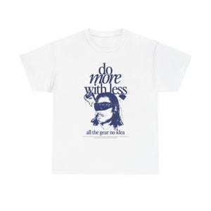 Puede incluir: Camiseta blanca con un gráfico azul marino. El gráfico presenta un retrato estilizado de una persona con gafas de sol, con las palabras "do more with less" arriba y "all the gear no idea" abajo. La camiseta es de cuello redondo clásico.