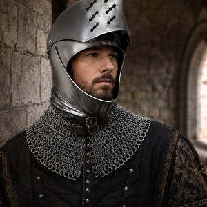 Può includere: Un elmo medievale in metallo lucido, con visiera e fessure di ventilazione. Indossato con un collare di maglia di catena e un farsetto nero trapuntato con finiture dorate, che evoca un'armatura storica.