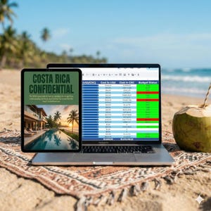 May include: A laptop and tablet on a patterned blanket on a sandy beach. The tablet displays "COSTA RICA CONFIDENTIAL" with a photo of a pool and palm trees. The laptop shows a spreadsheet with financial data and a coconut with a straw.