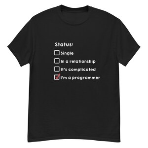 Puede incluir: Camiseta negra con texto blanco. El texto dice "Status:" seguido de casillas de verificación. La casilla junto a "I'm a programmer" está marcada. Otras opciones son "Single", "In a relationship" y "It's complicated".