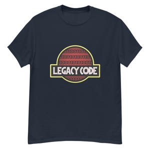Puede incluir: Camiseta azul marino con la inscripción "LEGACY CODE" en amarillo y blanco, sobre un fondo de código binario rojo. La camiseta tiene cuello redondo y mangas cortas, un estilo clásico.