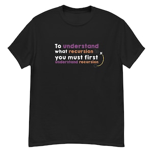 Puede incluir: Camiseta negra con el texto "To understand what recursion is, you must first understand recursion" en blanco, morado y amarillo. El diseño incluye un diagrama de juego.