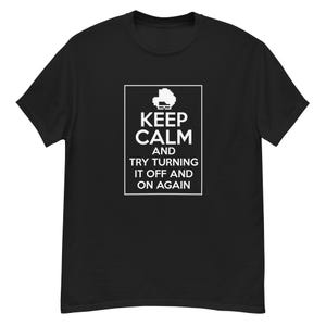 Puede incluir: Camiseta negra con el texto "KEEP CALM AND TRY TURNING IT OFF AND ON AGAIN" en un recuadro blanco. La camiseta tiene cuello redondo y mangas cortas. El texto está en una fuente sencilla, sin serifa.
