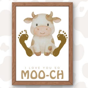 May include: A framed print featuring a watercolor illustration of a cartoon cow with brown spots and a smiling face. The cow is flanked by two brown footprints. The text "I LOVE YOU SO MOO-CH" is printed below the cow.