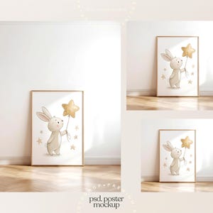 May include: A framed poster mockup featuring a watercolor illustration of a bunny holding a gold star balloon. The bunny is light brown with long ears. Gold stars are scattered around the bunny. The poster is displayed in a room with a wooden floor.