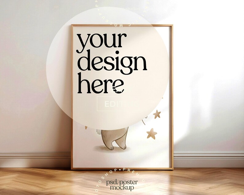May include: A framed poster mockup with the text "your design here" in black. The poster features a light brown illustration of a bear and gold stars. The frame is a light brown color, and the background is a light beige.
