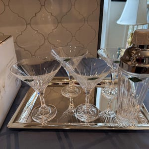 Peut inclure: Un ensemble de verres à martini en cristal transparent et un shaker à cocktails sur un plateau miroir argenté. Les verres ont une forme en V classique et des détails en verre taillé. Le shaker a un dessus argenté et un corps en verre clair.